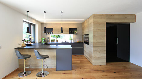Moderne Küche mit Insel in grau und Holzoptik, mit gemütlichem Sitzplatz