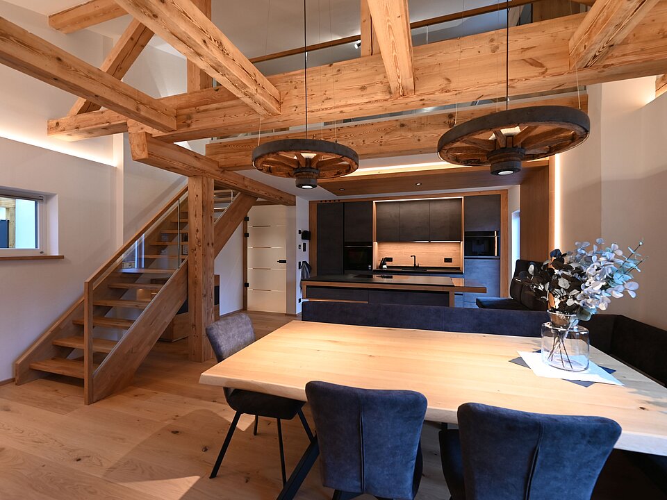 Wohnbereich mit dunkler Küche und Holztreppe