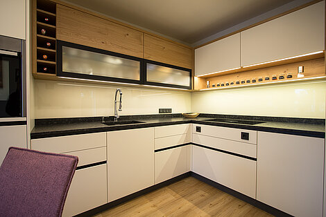 Eine weiße Küche mit Holz bei den Oberschränken