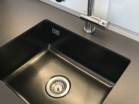 Schwarze Spüle mit geradliniger Armatur