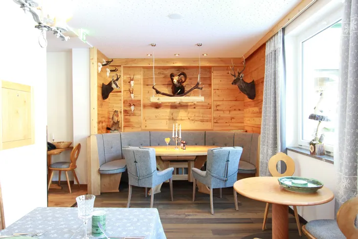 Gemütliche Sitzecke in einem rustikalen Restaurant mit Holzverkleidung und Jagdtrophäen an der Wand