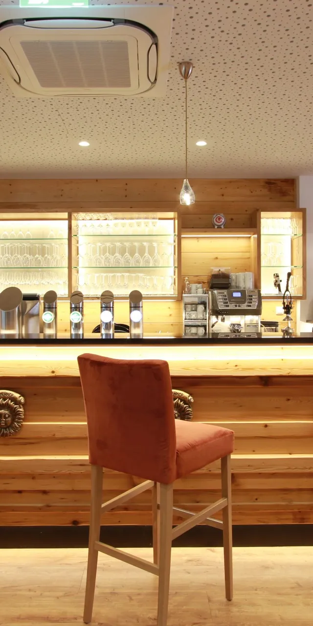 Moderne Hotelbar mit Holztheke, Barhockern und stilvoller Beleuchtung