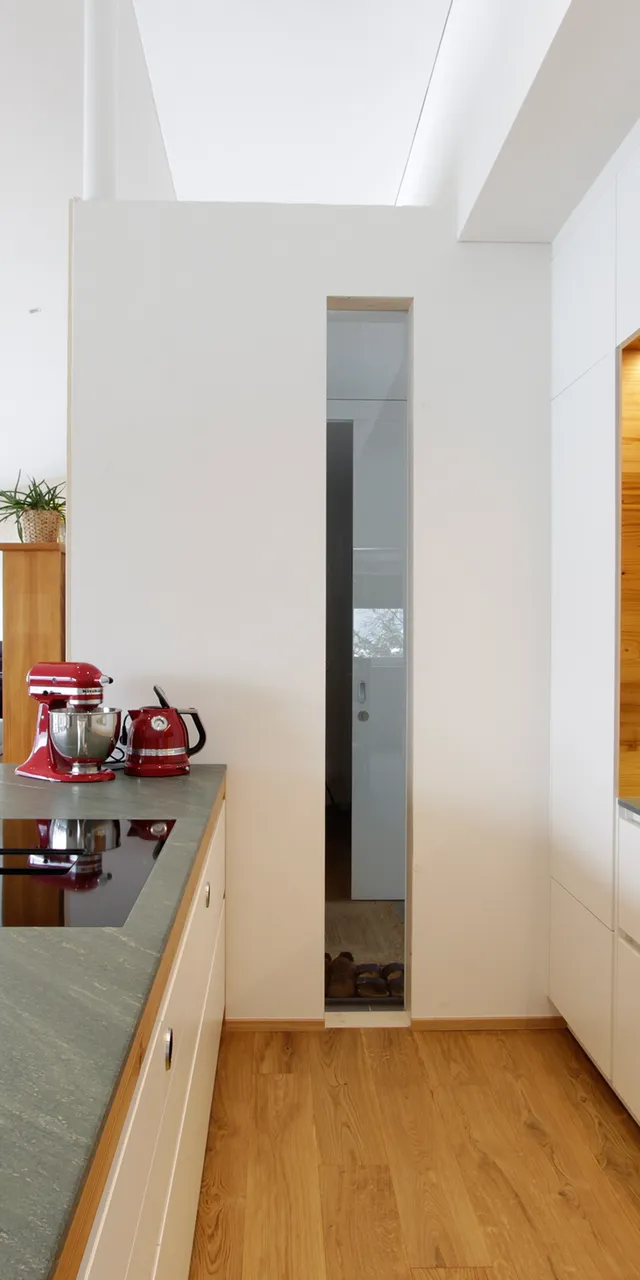 Moderne offene Küche mit Holzverkleidung, Induktionsherd und roten Küchengeräten