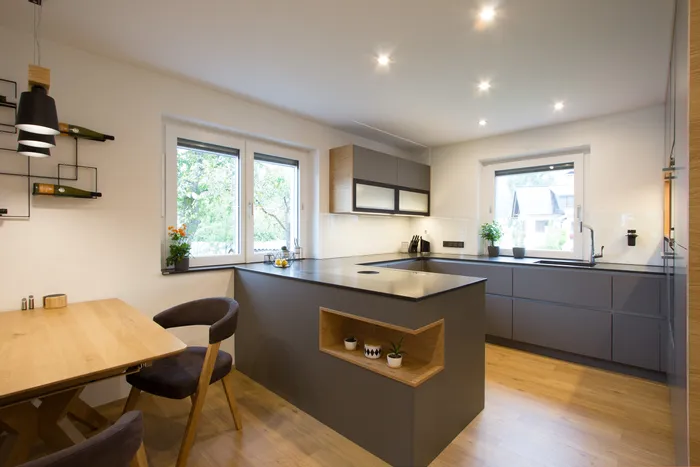 Moderne Einbauküche mit grauen Fronten, Kochinsel, Holzdetails und Essbereich mit Holztisch