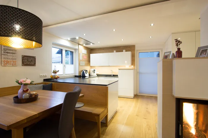 Moderne offene Wohnküche mit Holzboden, Kamin und stilvoller Beleuchtung