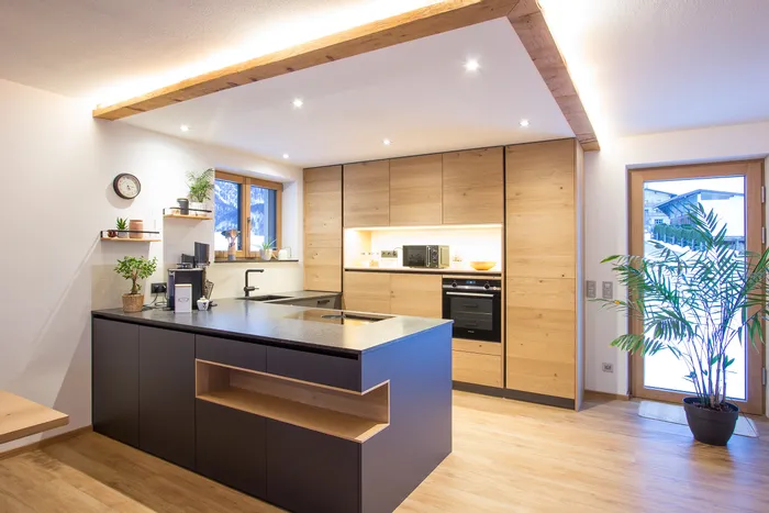 Moderne Einbauküche mit Holzfronten, Kücheninsel und Blick auf verschneite Landschaft