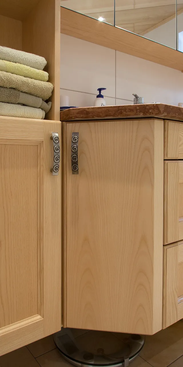 Modernes Badezimmer mit Holzunterschränken, gefalteten Handtüchern und einer Waschmaschine