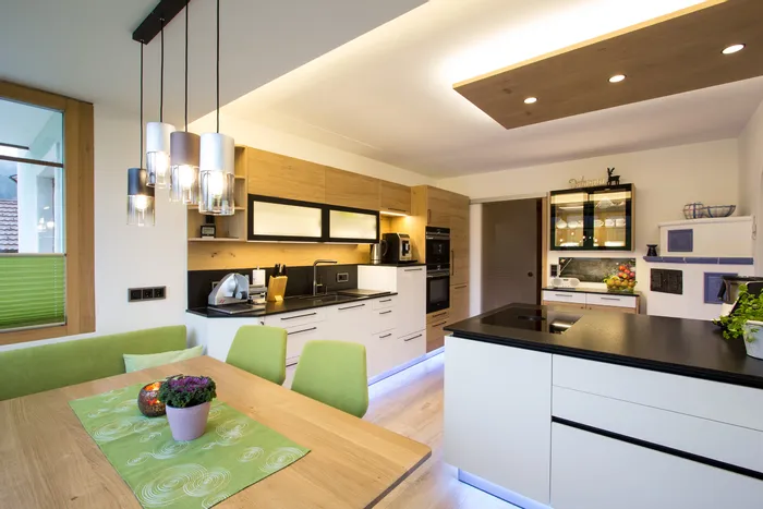 Moderne Küche mit Holzfronten, schwarzer Arbeitsplatte und LED-Beleuchtung unter Schränken