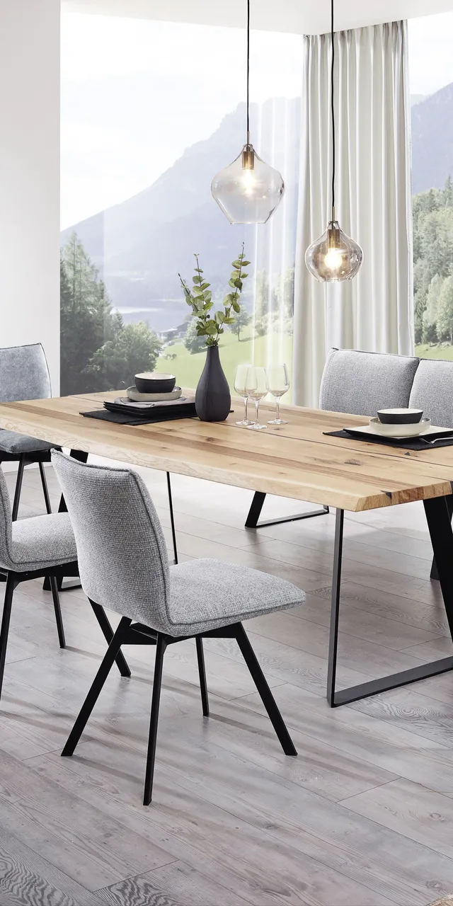 Modernes Esszimmer mit Holztisch, grauen Polsterstühlen und Panoramablick auf die Berge
