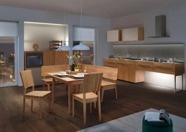 Moderne Wohnküche mit Holzmöbeln, Esstischgarnitur und stilvoller Beleuchtung bei Nacht