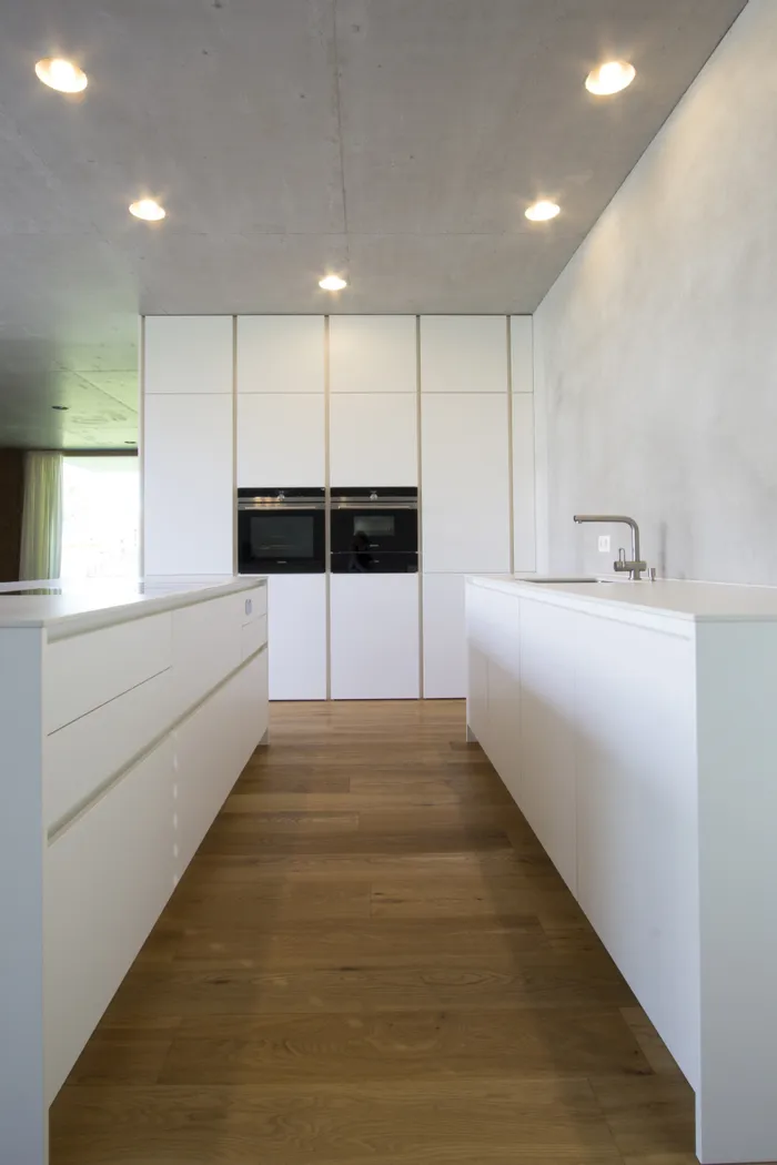 Moderne weiße Designküche mit Einbaugeräten und Holzfußboden