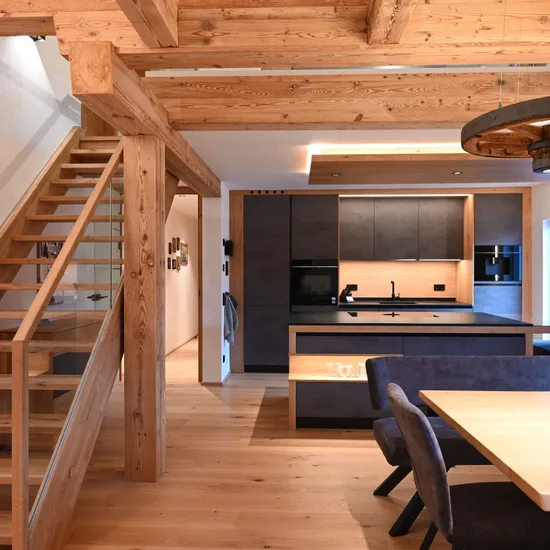 Moderne Küche und Essbereich mit Holzdecke, Treppe und dunklen Möbeln im Landhausstil