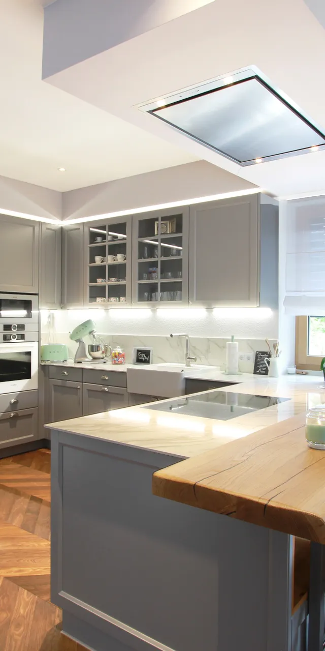 Moderne graue Einbauküche mit Kücheninsel, Holzboden und hochwertigen Elektrogeräten