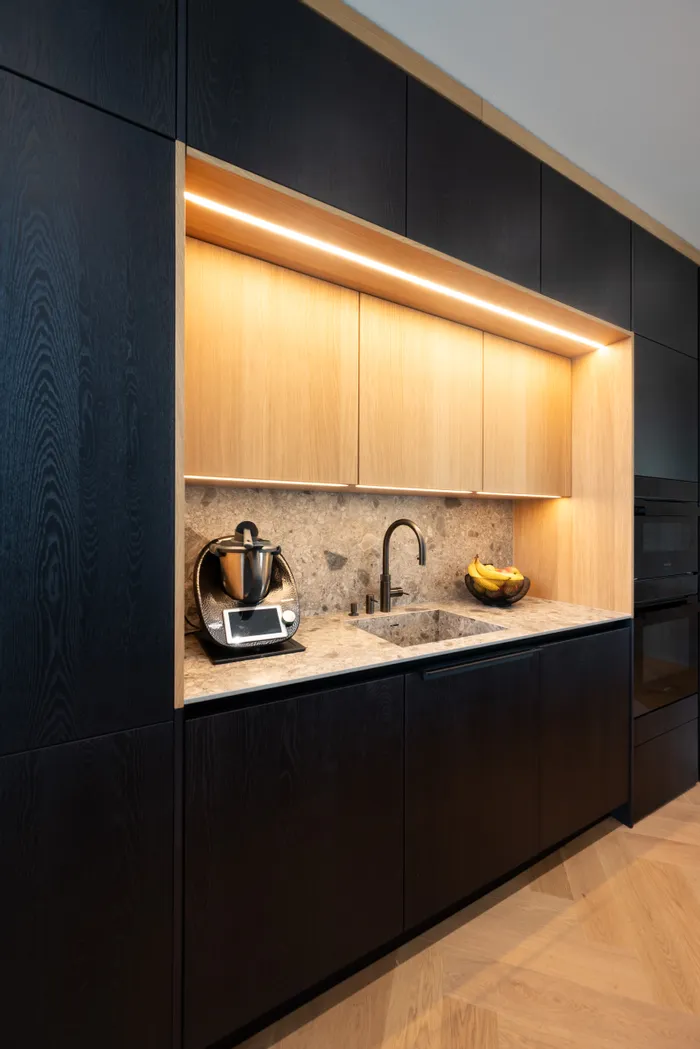 Moderne Einbauküche mit dunklen Schränken, Naturstein-Arbeitsplatte und Küchenmaschine