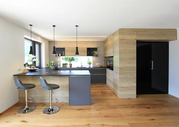 Moderne Küche mit Insel in grau und Holzoptik, mit gemütlichem Sitzplatz
