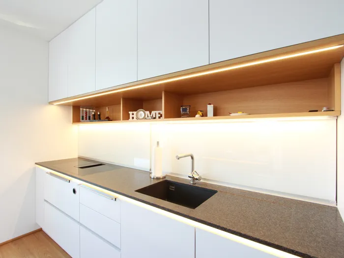 Weiße Küche mit schwarzer Arbeitsplatte und Holznische