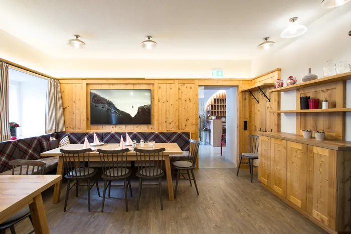 Gemütlicher Gastraum mit Holzmöbeln, gedecktem Tisch und Wandbild in alpinem Stil