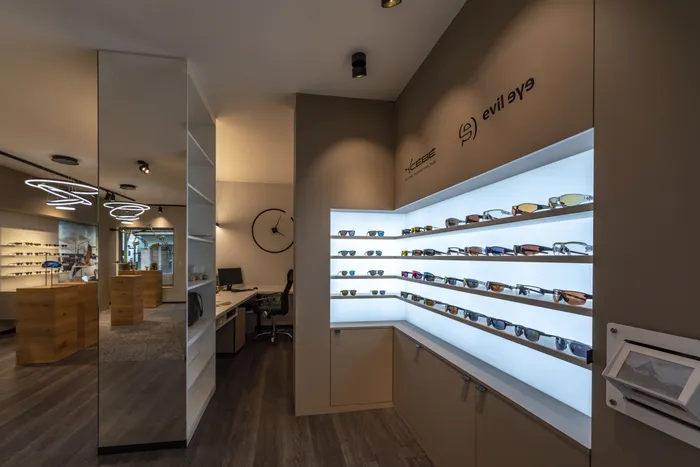 Modernes Optikgeschäft mit beleuchteten Regalen voller Sportsonnenbrillen