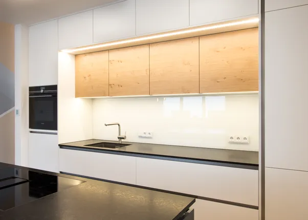 Moderne Einbauküche mit weißen Schränken, Holzoberschränken und schwarzer Arbeitsplatte