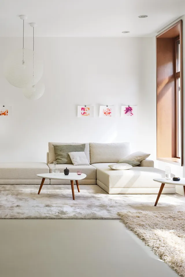 Modernes Wohnzimmer mit beiger Eckcouch, großen Fenstern und minimalistischer Dekoration