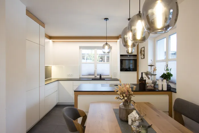 Moderne offene Küche mit weißen Schränken, Holzdetails und stilvollen Hängelampen