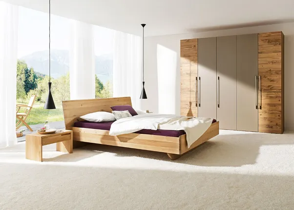 Modernes Schlafzimmer mit Holzbett, Nachttisch, großem Kleiderschrank und Panoramafenster mit Naturblick