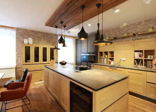 Moderne Küche mit Holzmöbeln, Kücheninsel, Hängelampen und Steinwand