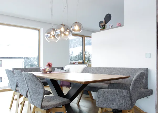 Modernes Esszimmer mit Holzfußboden, grauen Stühlen und hängenden Kugelleuchten