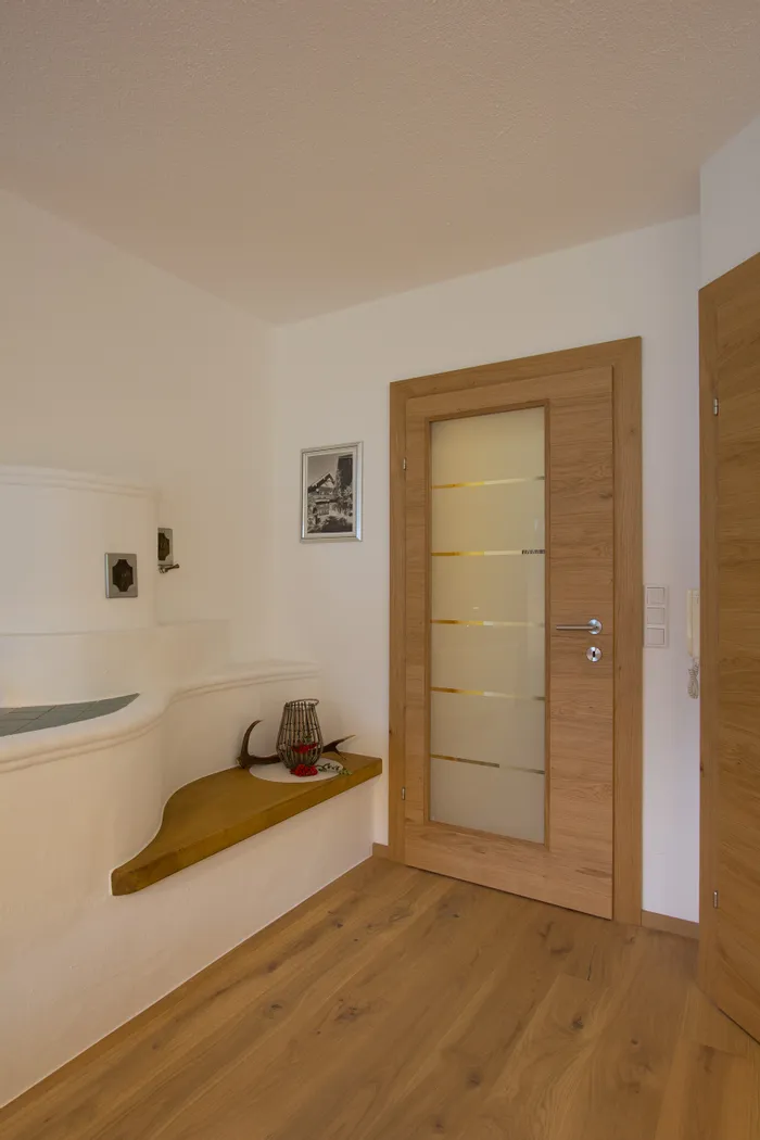 Eingangsbereich mit Holztür, Keramikkachelofen und Dekoration auf Holzbank