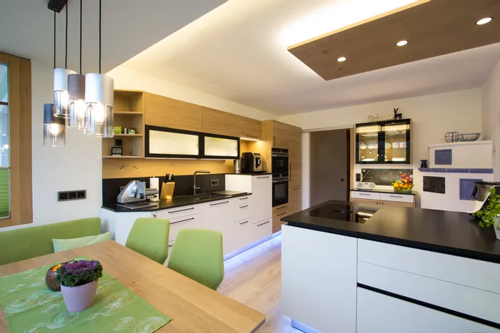 Moderne Einbauküche mit Holzfronten, LED-Beleuchtung und grünem Essbereich