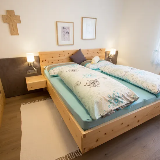 Modernes Schlafzimmer mit Doppelbett aus hellem Holz und gemusterten Bettdecken