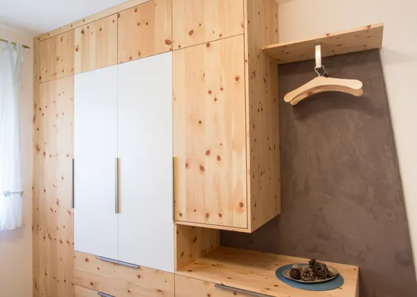 Moderner Einbauschrank aus hellem Holz mit weißen Türen und offener Garderobe im Schlafzimmer