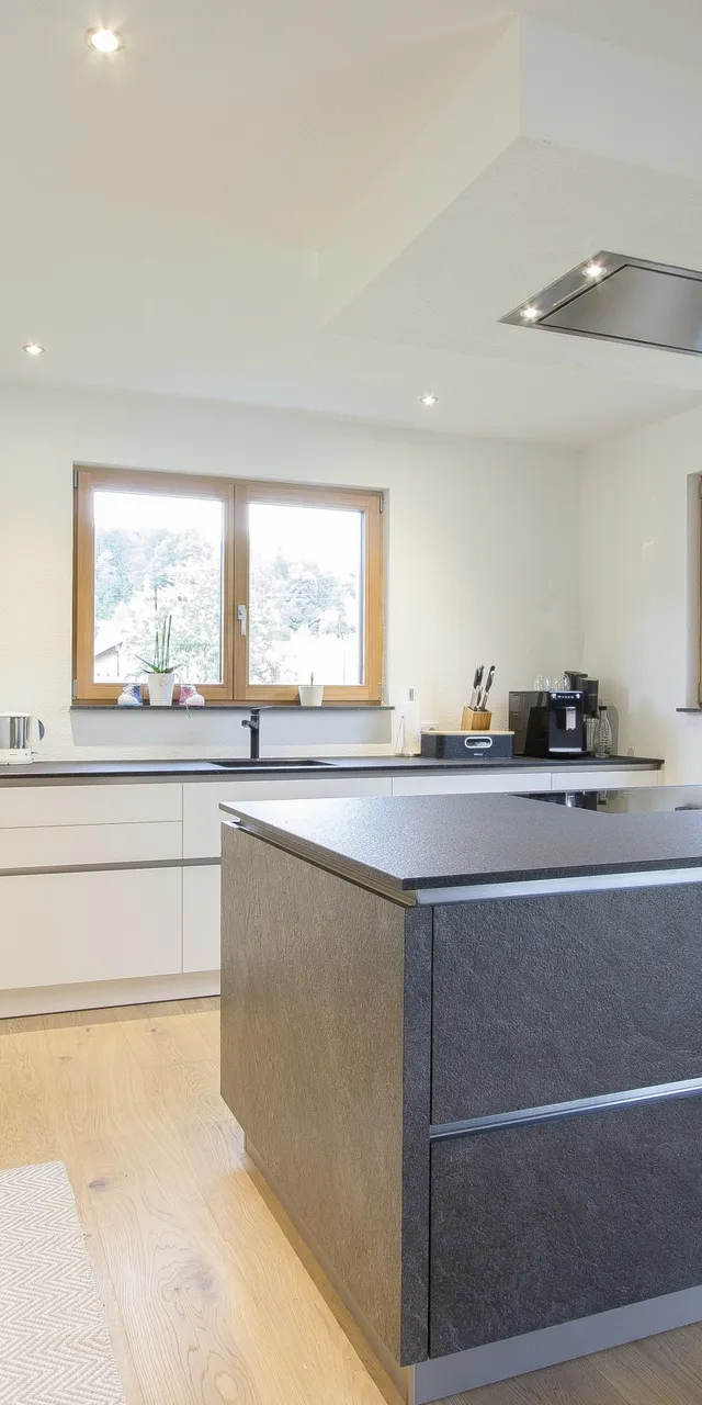 Moderne Einbauküche mit Kochinsel, Holzfußboden und großen Fenstern mit Bergblick