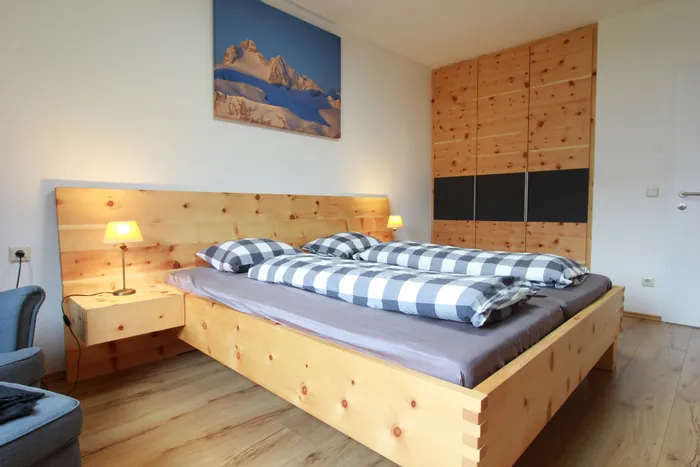Modernes Schlafzimmer mit Massivholzbett, karierten Bettdecken und eingebautem Holzschrank