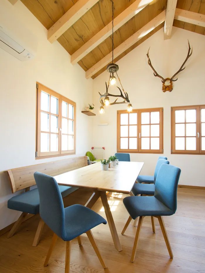 Heller Essbereich mit Holztisch, blauen Stühlen und rustikalem Hirschgeweih-Lüster