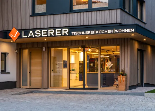 Moderne Fassade der Tischlerei Laserer mit beleuchtetem Küchenstudio-Eingang