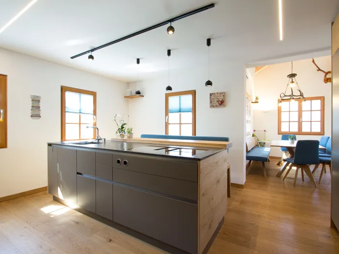 Moderne offene Küche mit Kochinsel, Holzfußboden und Essbereich mit blauen Stühlen