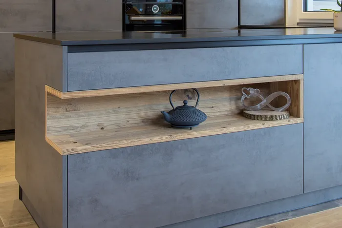 Moderne Kücheninsel mit offenem Holzregal, schwarzer Teekanne und Dekoration