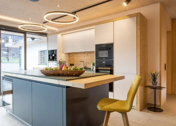 Moderne Küche mit Kochinsel, Obstschale, Einbaugeräten und stilvoller Beleuchtung