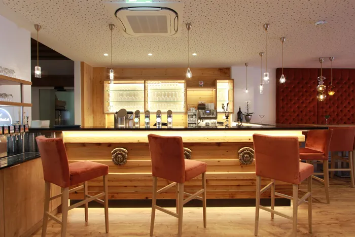 Moderne Hotelbar mit Holztheke, Barhockern und stilvoller Beleuchtung