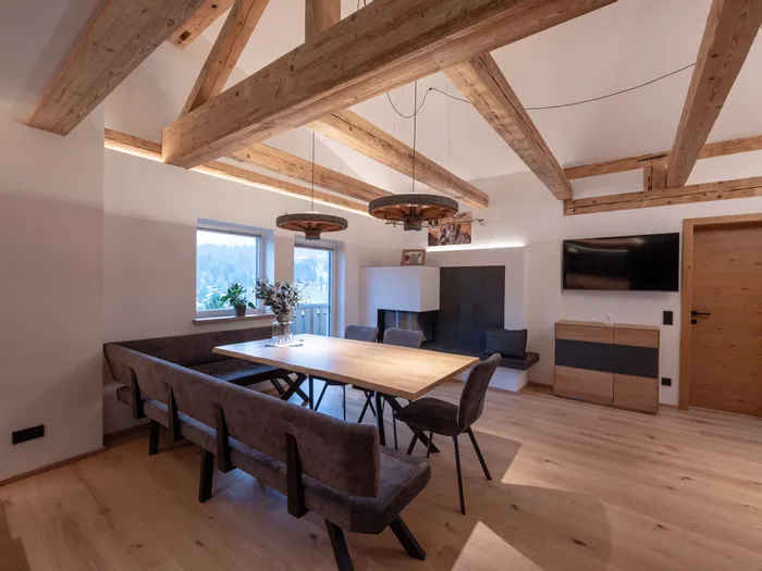 Moderne Esszimmereinrichtung mit Holzdecke, Esstisch und Polsterbänken in alpinem Stil