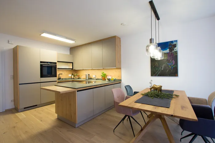 Moderne Einbauküche mit Holzdetails, Kücheninsel und Essbereich mit stilvollen Stühlen