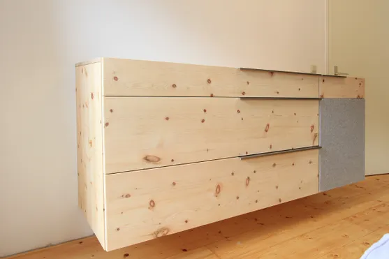Moderne schwebende Kommode aus hellem Holz mit grauer Filzfront an der Wand montiert