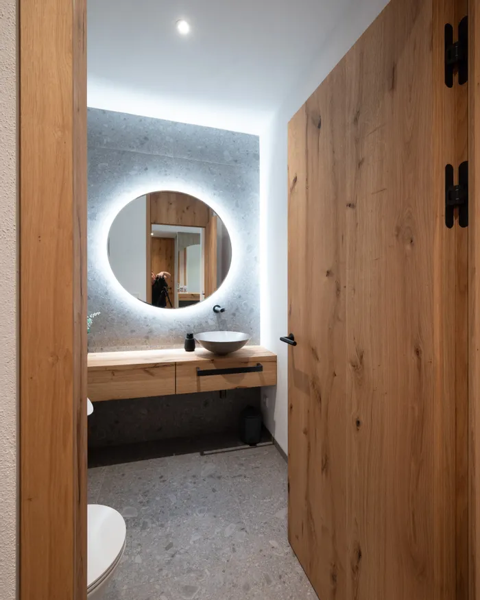 Modernes Badezimmer mit runder LED-Spiegelbeleuchtung und Holzwaschtisch