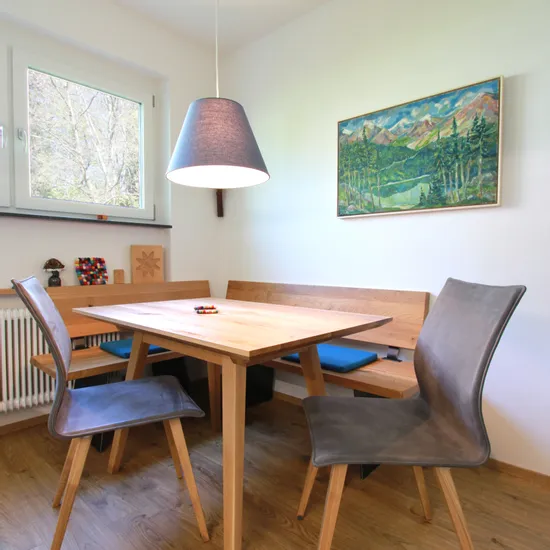 Moderne Essecke mit Holztisch, grauen Stühlen und Landschaftsbild an der Wand