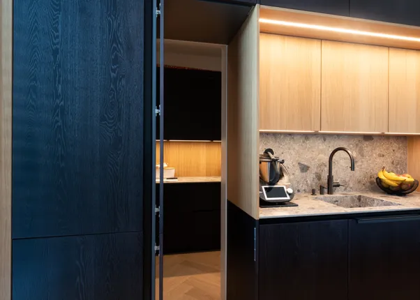 Moderne Küche mit dunklen Schränken, Marmorarbeitsplatte und versteckter Speisekammer