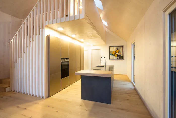 Moderne offene Küche mit Holzverkleidung, Kochinsel und Einbauschränken in Goldoptik