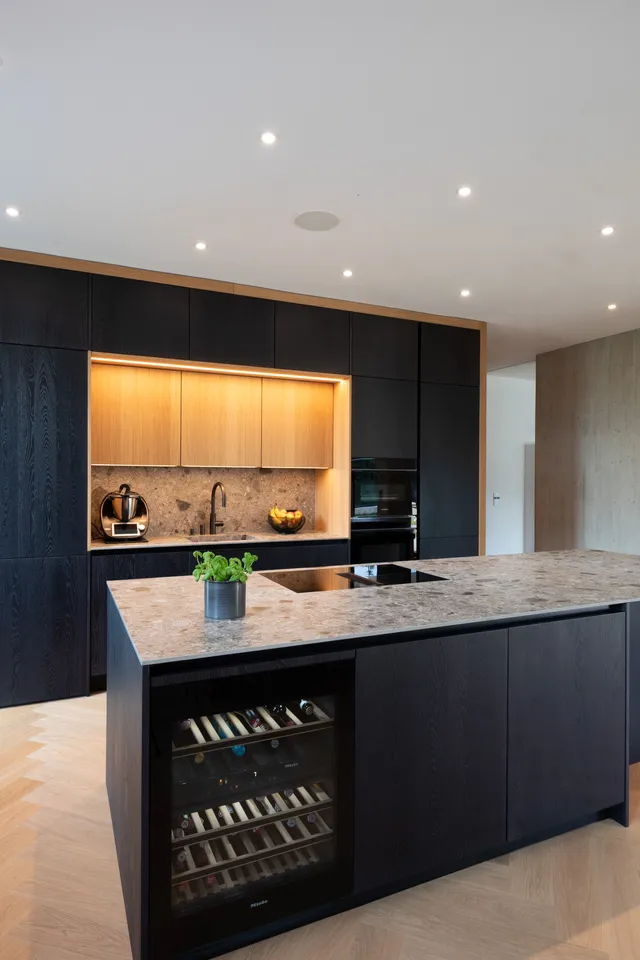 Moderne Küche mit dunklen Schränken, Kochinsel mit Marmorplatte und integriertem Weinkühlschrank