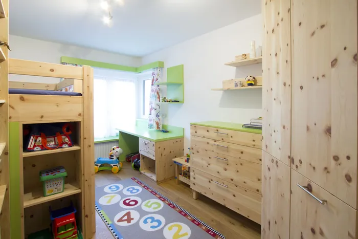 Helles Kinderzimmer mit Holzmöbeln, Etagenbett, Spielzeugregal und buntem Zahlen-Teppich