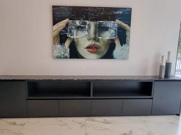 Modernes Sideboard mit Marmorplatte und Kunstbild einer Frau mit Glaswürfeln vor den Augen